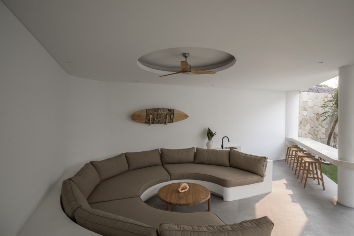 Outdoor lounge with curved sofa and bar seating area at Jipsi Villas Canggu Bali