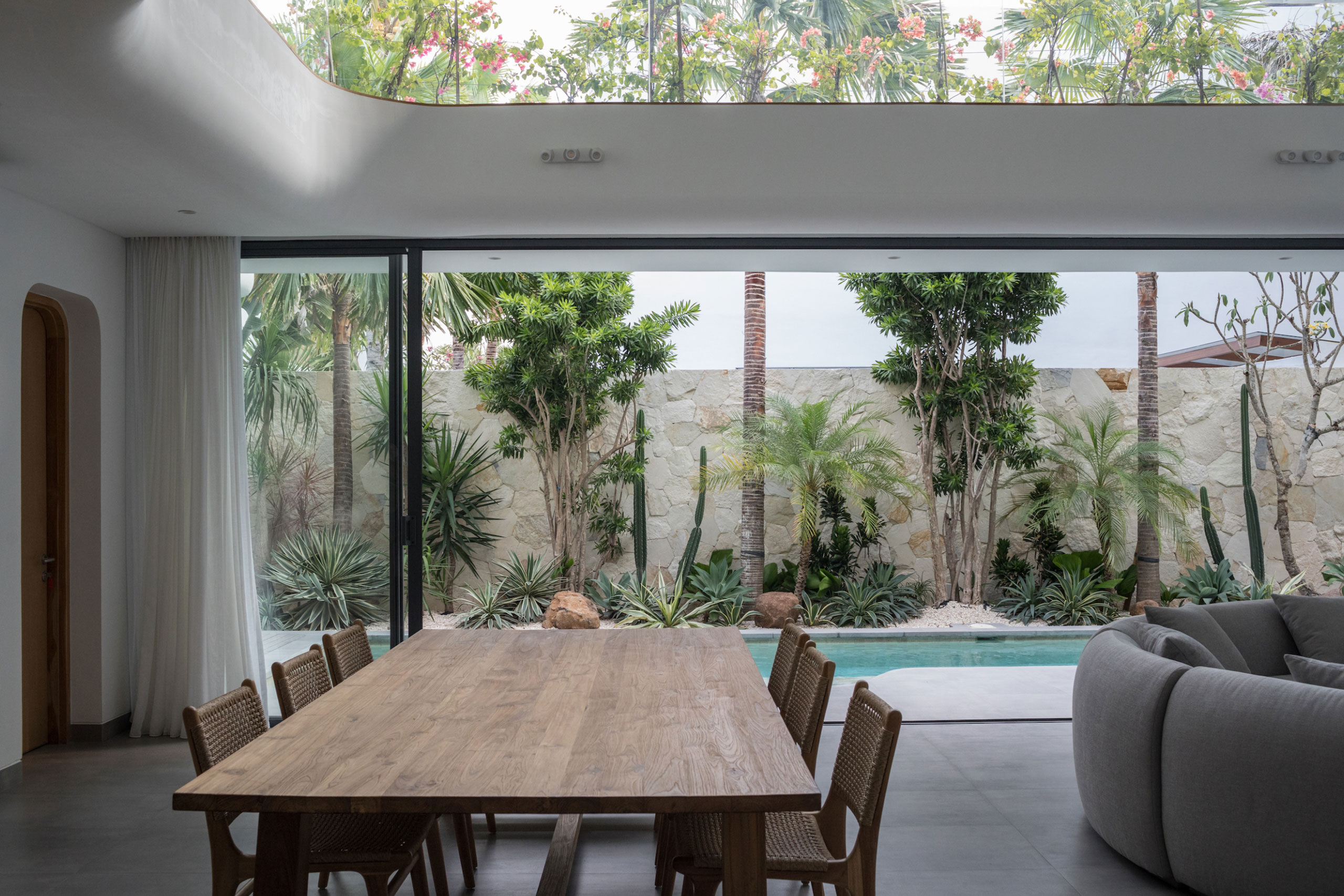 Dining area with pool and tropical garden view inside modern villa at Jipsi Villas Bali.