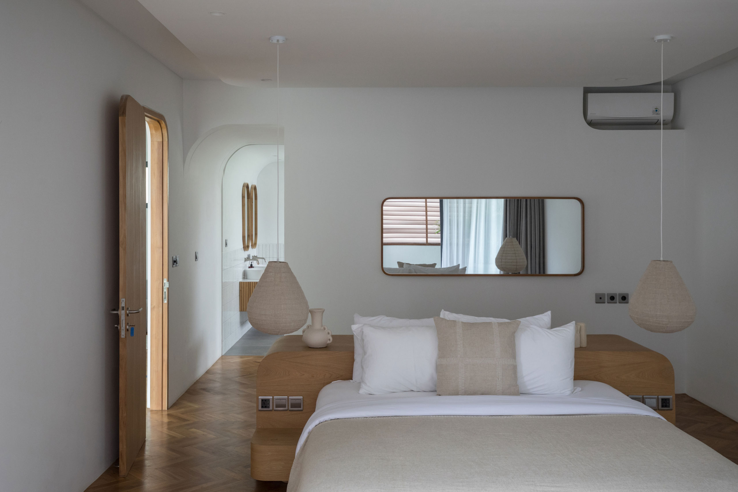 Minimalist bedroom with wooden furniture and ensuite bathroom at Jipsi Villas Bali