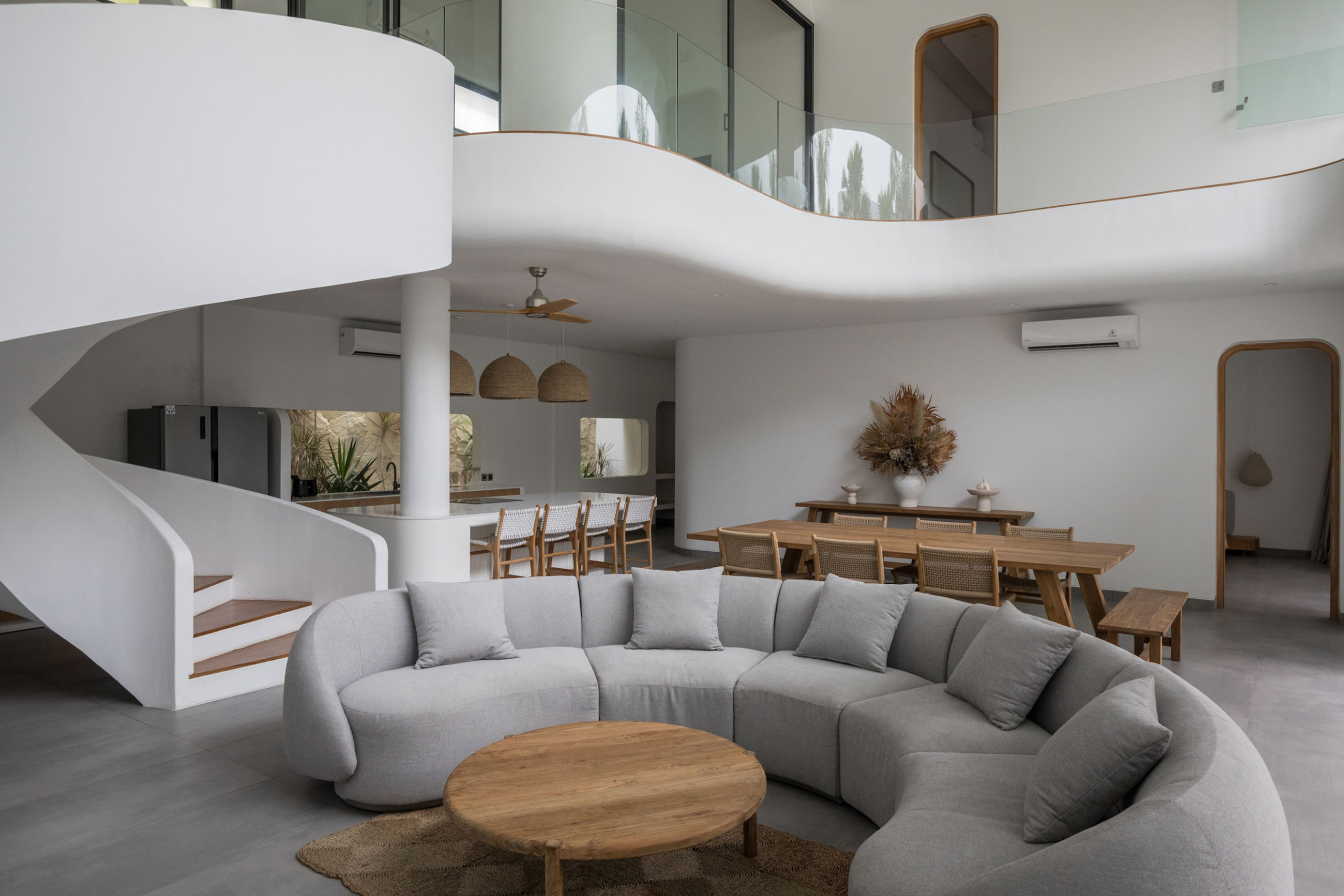Spacious open-plan living and dining area with modern spiral staircase at Jipsi Villas Bali