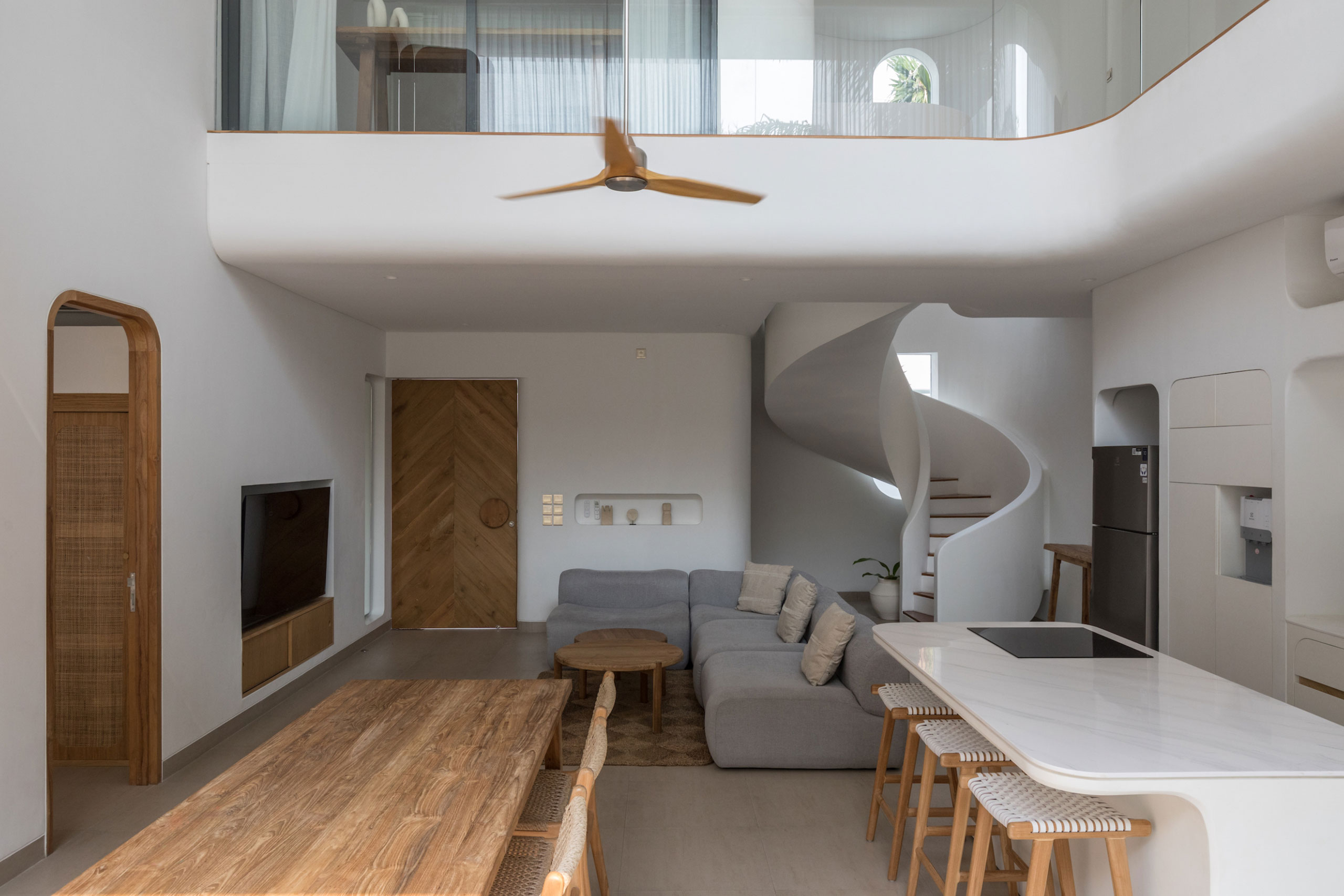 Modern living room with spiral staircase and wooden dining area at Jipsi Villas Bali