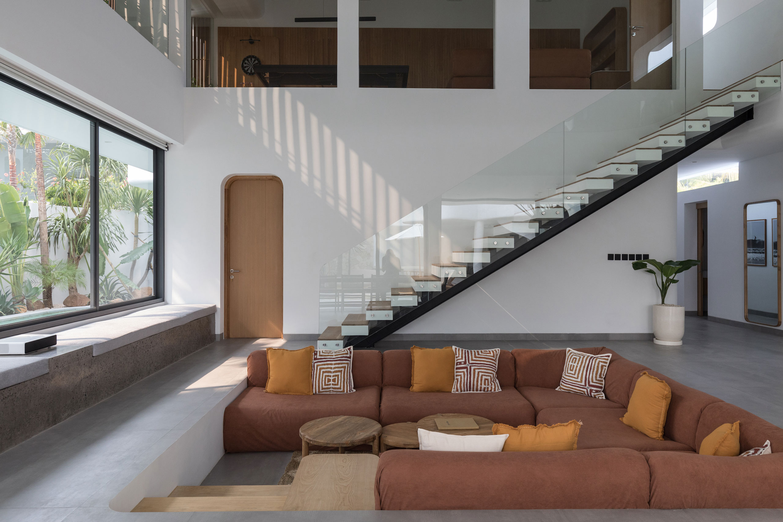 Modern sunken living room with glass staircase at Jipsi Villas Bali.