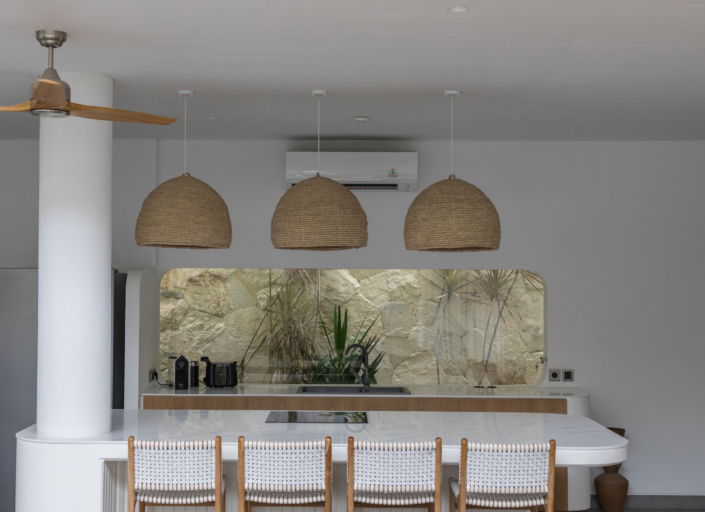 Modern minimalist kitchen with natural rattan lamps and white island at Jipsi Villas Canggu Bali