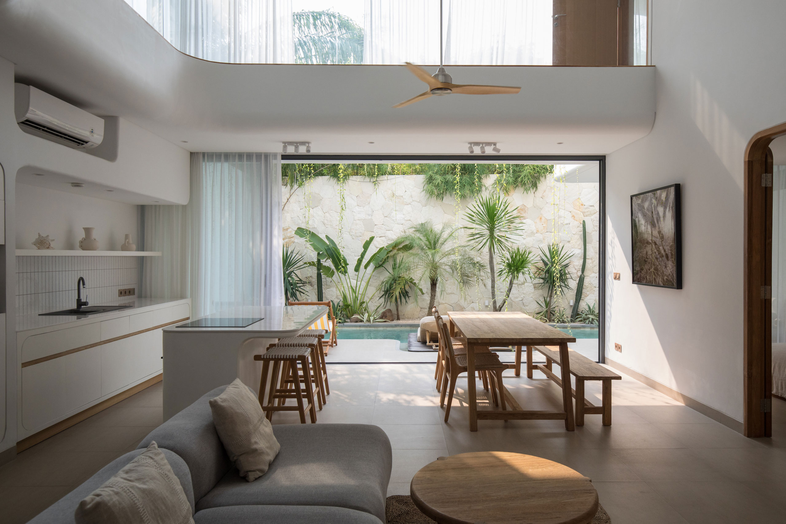 Modern open kitchen and dining area with pool and tropical garden view at Jipsi Villas Bali