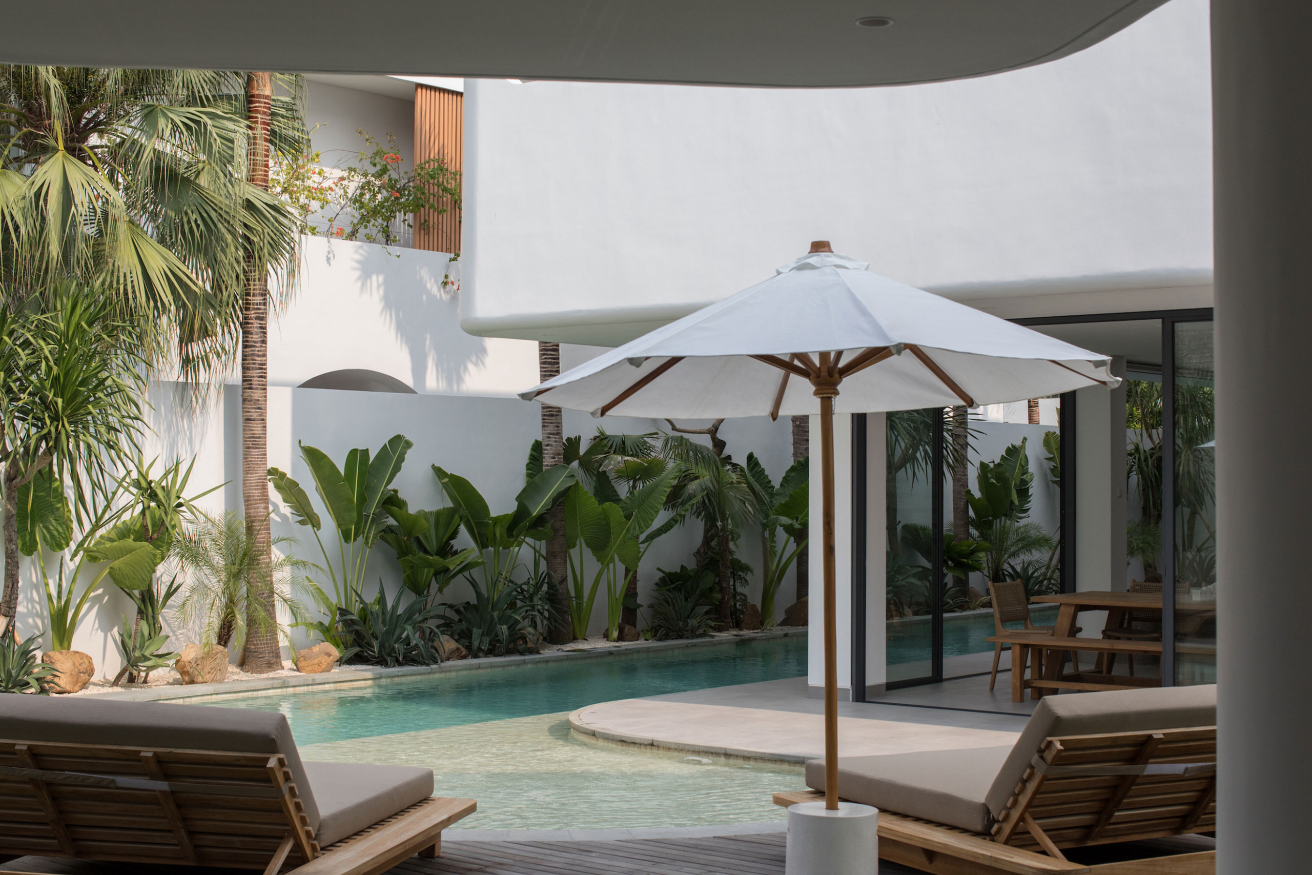 Private pool with sun loungers and tropical garden at Jipsi Villas Bali